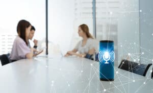 a smart speaker sitting on a board room table with three people talking in the background